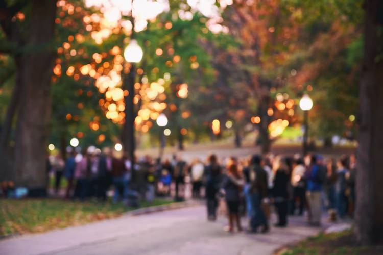 blurry image of an evening event outside with string lights and people roaming about