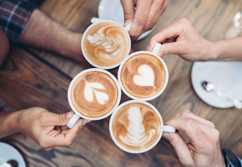 four people holding coffee cups with foam art on top aerial view